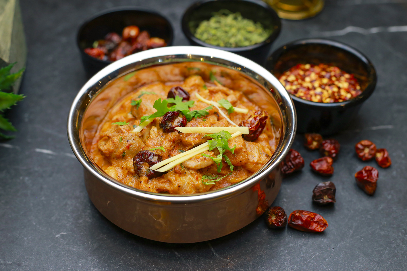 Curry in a copper handi with dried chillies