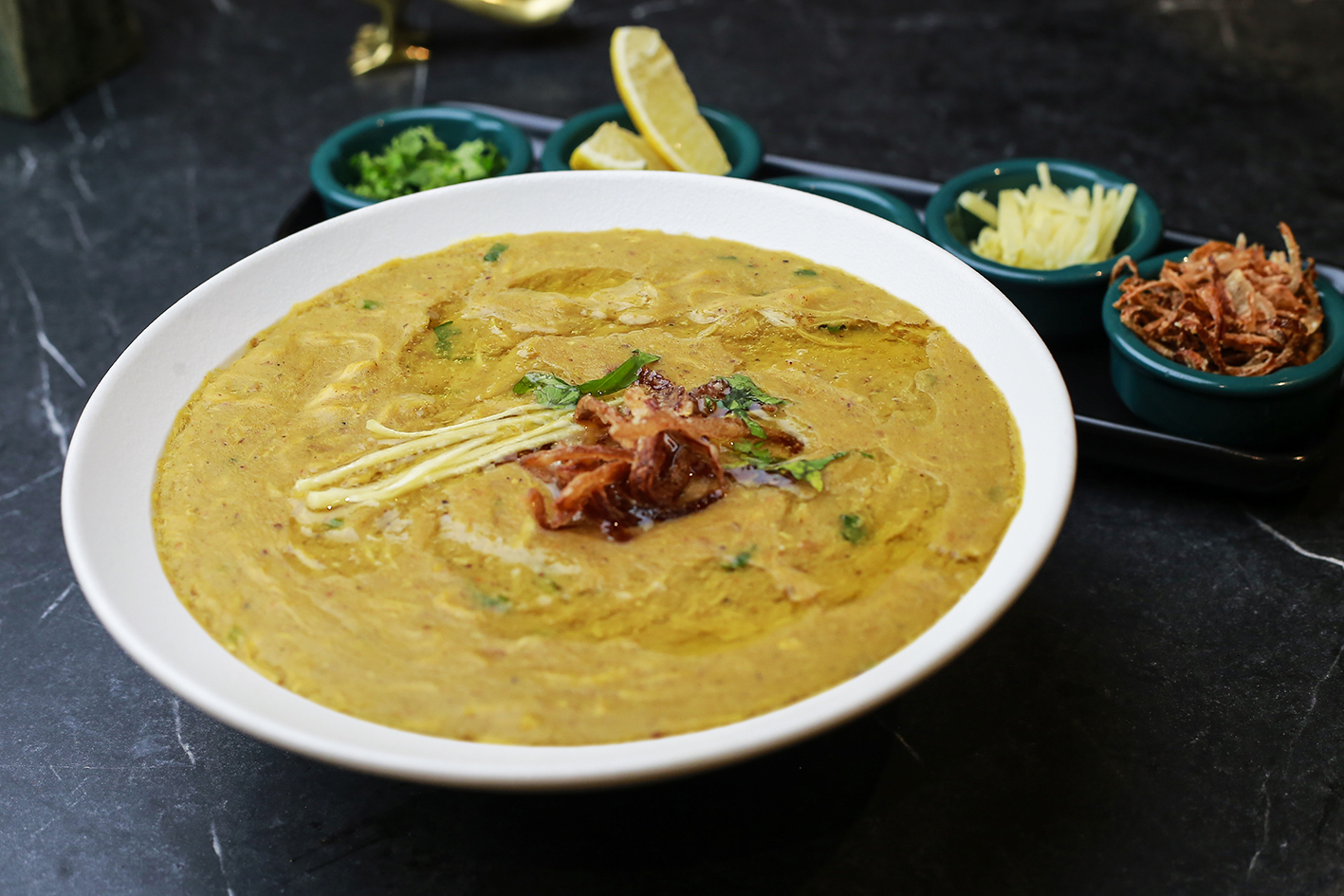 Bowl of haleem with fried onions and ginger